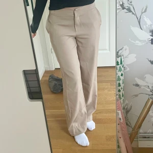 Lågmidjade kostymbyxor - Beiga lågmidjade kostymbyxor från NA-KD i storlek 36. Bra skick, använda endast ett fåtal gånger. Har sytt upp dem själv (jag är 1.73 cm)🌸🫶🏻