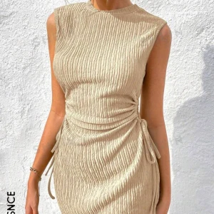 En beige klänning  - En beige klänning med resorband på sidorna.