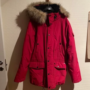 Jacka från Carhartt - Röd och fin vinterjacka i bra skick, tyvärr finns några fläckar av okänd härkomst som jag inte lyckats få bort bak på högeraxeln. Storlek L Märke: Carhartt   Tveka inte att skriva om du har frågor.