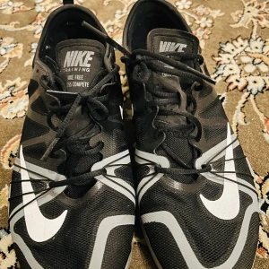 Svarta Nike träningsskor - Säljer ett par svarta Nike träningsskor, modell Nike Free Cross Compete. De har en snygg design med vita detaljer och snörning. Perfekta för träning och vardagsbruk. Skorna är i bra skick och redo för nya äventyr!
