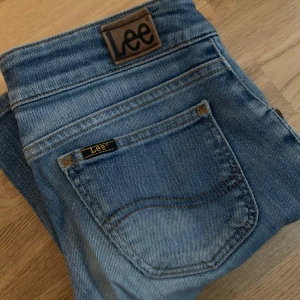 Lågmidjade jeans från Lee - Lågmidjade blåa bootcut jeans från märket Lee. Storlek W27 L31. Säljer för att de är för små💕