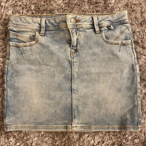 LTB Demin kjol - Jeans kjol i blå demin ’Adrea’. Det är en lågmidjad minikjol med neutrala färger och en smal passform. Den har dragkedja och 5 fickor. Storlek S  (Använd 0 gånger, oanvänd)