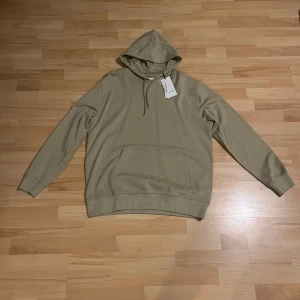 Beige hoodie från Lindbergh - Säljer en snygg beige hoodie från Lindbergh i storlek XXL. Den är helt ny med taggar kvar. Perfekt för en avslappnad stil och passar bra till både höst och vår. Skön och stilren design!