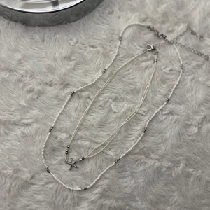 Dubbelhalsband med sjöstjärna - Snyggt dubbelhalsband med en cool sjöstjärna som hänge från new yorker. Det ena halsbandet har små vita pärlor och silverfärgade detaljer, medan det andra är en tunn tråd. Perfekt för att ge en strandig vibe till din outfit! 🐚✨