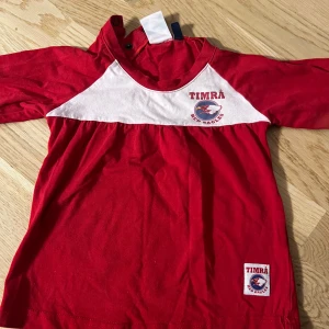 Röd Timrå tröja för barn skriv vad ni skulle villa ge  - Säljer en superfin röd tröja från Timrå Red Eagles för barn. Tröjan har vita detaljer och ett tryck med Timrås logga på bröstet. Perfekt för små fans som vill visa sitt stöd! Tröjan är i bra skick och redo för nya äventyr. Storlek 86/92