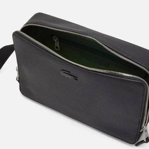 Svart axelväska från Lacoste - Snygg och stilren svart axelväska från Lacoste i syntetmaterial. Väskan har en praktisk dragkedja och en justerbar axelrem. Perfekt för vardagsbruk eller när du är på språng. Den har en diskret logga på framsidan och ett rymligt fack inuti. Axelremsväska. Kvitto finns köpt i zalando 