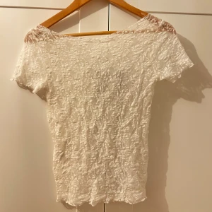 Vit spetsblus - Säljer en superfin vit spetsblus i mycket bra skick. Den är kortärmad och har en elegant offshoulder-design. Perfekt för sommarens alla fester eller en mysig vårdag. Materialet är lätt och luftigt, vilket gör den bekväm att bära hela dagen. Kragen har jag själv klippt så att den är i offshoulder look. Köpt utomlands flera år sen aldrig kommit till användning. Mycket vitare färg än i bilden!!!