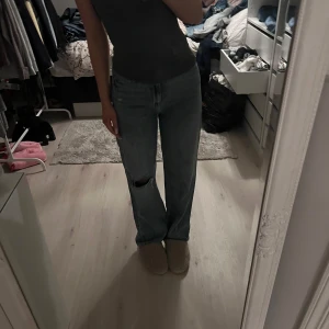 Blå jeans med hål - Säljer ett par blå jeans i bra skick. De har en straight passform och ett snyggt hål på ena benet för en avslappnad look. Perfekta för vardagsbruk och kan matchas med det mesta i garderoben.