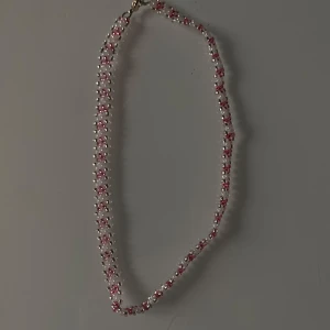 Pärlhalsband med rosa och vita detaljer - Säljer ett superfint pärlhalsband med små rosa och vita pärlor. Perfekt för att ge en söt touch till din outfit. Halsbandet har en enkel låsning och är lätt att bära till både vardag och fest. Passar perfekt till sommarens alla tillfällen! 💖