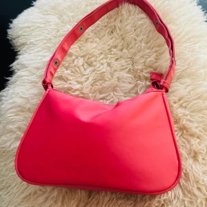 Snygg Ljus rod axelväska – färgglad & stilren - Snygg röd axelväska i syntet med justerbar rem och tryckknappar. Perfekt för en färgglad touch till alla outfits!