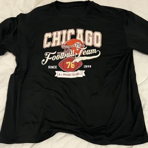 Svart t-shirt med Chicago-tryck - Säljer en svart t-shirt med coolt Chicago Football Team-tryck på framsidan. Perfekt för vardagsbruk eller sportiga tillfällen. T-shirten har en normal passform och är kortärmad, vilket gör den bekväm och lätt att bära. Passar perfekt för dig som gillar sportig stil!oversized säljs för 60