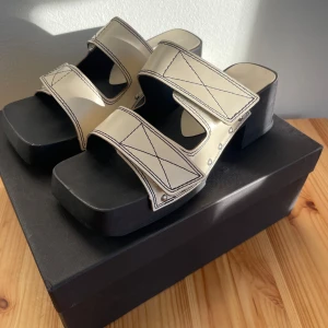 Sandaler från Miista - Snygga sandaler från Miista i svart och créme vitt -  oanvända, endast provade. Träsula och ascool fyrkantig tå. Köpte dyrt från England men var tyvärr för stor för mig som egentligen är 35a så säljer igen. Kartong följer med. 
