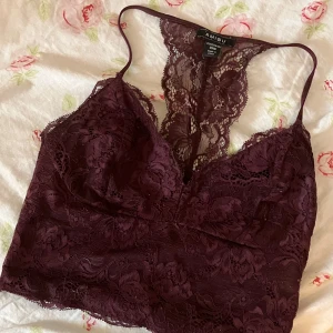 Vinröd spetslinne från Amisu - Säljer ett snyggt vinrött spetslinne från Amisu. Linnet har en vacker spetsdesign med smala axelband och en djup v-ringning.