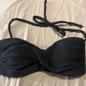 Svart bikiniöverdel från Stadium - Snygg svart bikiniöverdel från Stadium med knytband runt nacken och en elegant omlott-design framtill. Perfekt för en dag på stranden eller vid poolen. Aldrig använd👏🏼
