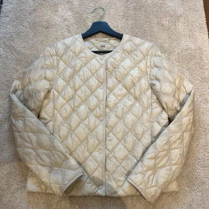 Beige quiltad jacka från Uniqlo - Säljer en stilren beige quiltad jacka från Uniqlo. Jackan har en rund halsringning och långa ärmar, perfekt till våren. 👏🏼🥹
