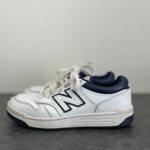 Vita sneakers från New Balance - Snygga vita sneakers från New Balance med marinblå detaljer och snörning. 