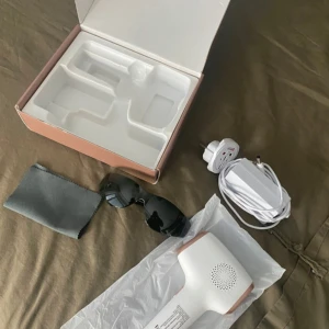 IPL hårborttagningsenhet - Säljer en IPL hårborttagningsenhet i vitt med detaljer i roséguld. Inkluderar solglasögon och rengöringsduk. Perfekt för smidig och effektiv hårborttagning hemma. Oanvänd, säljer pga att jag fått en annan modell i present. Köpt den för 1500, säljer för 500