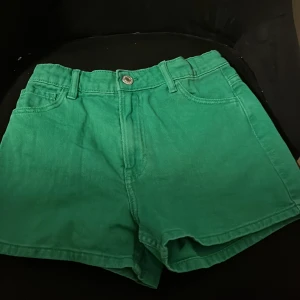 Gröna shorts från H&M - Snygga gröna shorts från H&M i en härlig färg. De har en klassisk design med knapp och dragkedja framtill samt två bakfickor. Perfekta för en avslappnad stil.