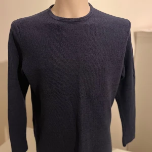 Mörkblå stickad tröja från Only & Sons - Snygg mörkblå stickad tröja från Only & Sons. Perfekt för kyligare dagar med sin mjuka och bekväma passform. Tröjan har långa ärmar och en rund halsringning. Ett stilrent val för en avslappnad look.