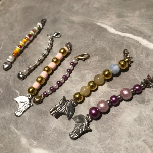 Hängare på nyckel, mm - Säljer ett set av fyra färgglada pärl sett med olika berlocker. har pärlor i olika färger som rosa, lila, guld och silver. unik berlock, inklusive hjärtan och hästhuvuden. Perfekt för att lägga till en personlig touch till din stil. Säljer alla för 200 kr en för typ 40kr