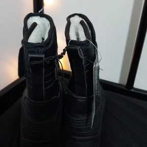 Svarta vinterstövlar från True North - Snygga och varma svarta vinterstövlar från True North med ett geometriskt mönster. De har en dragkedja framtill och är fodrade med mjukt vitt material för extra värme. Perfekta för kalla vinterdagar.