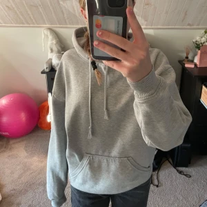 Grå hoodie från BikBok - Säljer en stilren grå hoodie från BikBok i storlek XS. Den har en klassisk design med känguruficka och justerbar huva med snören. Perfekt till ett par snygga jeans! Lite nopprig. Pris går att diskutera💕