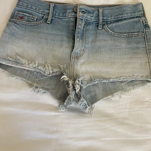 Ljusa jeansshorts från Hollister - Säljer ett par snygga ljusblåa lågmidjade jeansshorts från Hollister med fransiga kanter och en klassisk femficksdesign. Shortsen har en lågmidjad passform och en snygg sliten stil, perfekta för i sommar. Storleken ser du i bilderna (W27) de sitter som S/XS, perfekt passform. Helt nytt skick, hör av vid intresse så diskuterar vi ett pris 🤗❤️