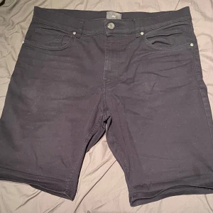 Svarta slim fit shorts från H&M - Snygga svarta slim fit shorts från H&M. Perfekta för en stilren look med fem fickor och knappgylf. Passar bra till både vardag och avslappnade tillfällen.
