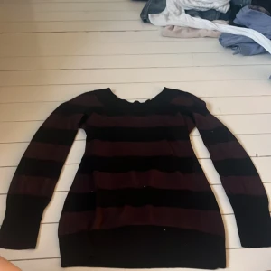 Svart och vinröd randig tröja från H&M - Säljer en svart och vinröd randig tröja från H&M. Tröjan har långa ärmar och är tillverkad i ett mjukt material som ger en bekväm passform. Perfekt för kyligare dagar.