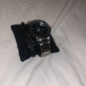 Stilren silverfärgad klocka regal - Säljer en stilren klocka i silverfärg med metallarmband. Klockan har en klassisk design med tre små urtavlor och tydliga markeringar. Perfekt för både vardag och fest. Passar bra till alla outfits och ger en elegant touch.