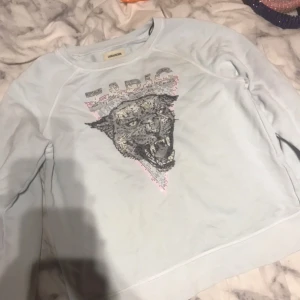 Ljusblå tröja med leopardtryck från Zadig & Voltaire - Snygg ljusblå tröja från Zadig & Voltaire med ett coolt leopardtryck i svart och rosa. Tröjan har långa ärmar och en avslappnad passform. Perfekt för en trendig look!