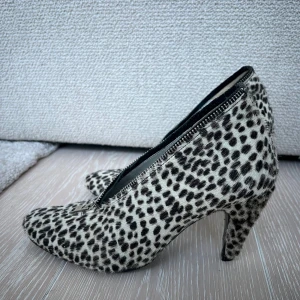 Leopardmönstrade klackskor med dragkedja - Snygga klackskor med leopardmönster och dragkedja framtill. Skorna har en spetsig tå och är perfekta för att ge en djärv touch till din outfit. Fluffiga och djurmönstrade - så fina! Varsamt använda. 