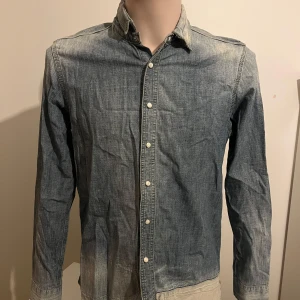 Jeansskjorta från Lee - Snygg jeansskjorta från Lee i en klassisk blå nyans. Skjortan har långa ärmar och knappar framtill. Perfekt för en avslappnad stil med en touch av denim.