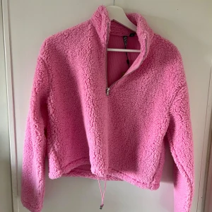 Rosa teddyjacka med dragkedja - Säljer en supergosig ljusrosa teddyjacka med halv dragkedja och justerbar nederkant. Prislappen sitter kvar, aldrig använd. Köpt ny för 329kr. 