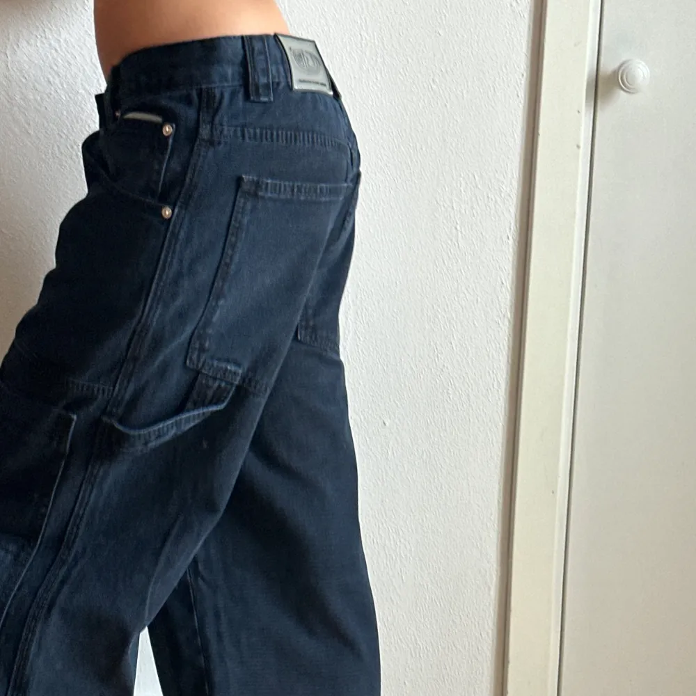 Mörkblå cargopants från Eytys med flera fickor och en cool ringdetalj vid midjan. Byxorna har en loose passform och är perfekta för en avslappnad stil. . Jeans & Byxor.