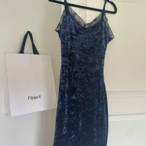 Mörkblå sammet klänning från Filippa K - Säljer en elegant mörkblå klänning i sammet. Den har en vacker spetsdetalj vid halsringningen och smala axelband. Perfekt för festliga tillfällen! Använts en gång vid nyår. 