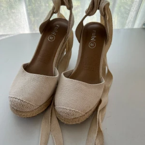 Vita kilklackar  - Krämiga kilklackar från rubi, strl 35. Sparsamt använda. Liten fläck i tyget på vänster sko.