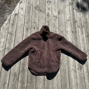 Brun teddyjacka från McKinley - Säljer en supermysig brun teddyjacka från McKinley i storlek small. Jackan är perfekt för höst och vinter med sitt varma och mjuka material. Den har en hög krage och långa ärmar, vilket gör den extra skön att ha på sig under kyliga dagar. Perfekt för både vardag och utomhusaktiviteter!