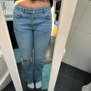 Gina Tricot jeans blåa Mid waist - Jag säljer nu mina blåa jeans från Gina Tricot med ett hål på ett knä, som har ett väldigt bra skick, då de använts vid ett fåtal tillfällen. Kan de stora ut men detta är pågrund av att jag köpte byxorna när jag var lite större i midjan💗