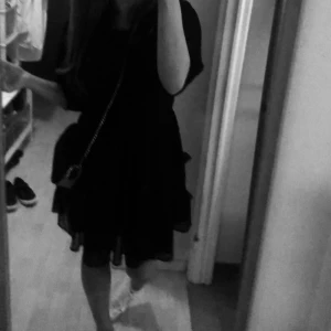 Svart kortklänning med volanger - Säljer en superfin svart klänning med volanger. Klänningen har trekvartsärmar och är perfekt för fest eller andra roliga tillfällen. Den är gjord av ett lätt och luftigt material med ett prickigt mönster. Klänningen har en lös passform. Perfekt för både sommar och höst! Köpte för ca 2 år sedan. Endast slitage på bandet man knyter på ryggen. 