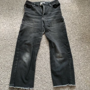 Svarta jeansbyxor från Lindex - Säljer ett par svarta jeansbyxor från Lindex i storlek EUR 158 / UK 12-13Y. Byxorna har en hög midja och en straight passform. De är tillverkade i bomull och har en rå kant vid bensluten för en cool look. Små hål mellan ben. Köparen betalar för frakt