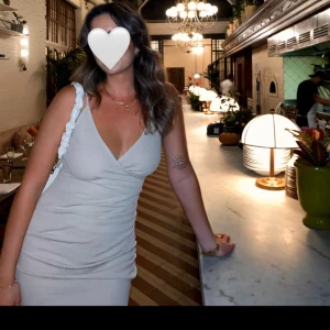 Vit omlottklänning - Säljer en superfin begie omlottklänning som är perfekt för fest eller sommar. Klänningen är ärmlös och har en v-ringad hals. Den är tight och har en snygg slits på sidan. Materialet känns som bomull. Perfekt för en utekväll eller en somrig dag!