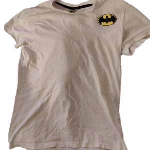 Säljer en cool vit t-shirt med Batman-logga på bröstet. Perfekt för alla superhjältefans! T-shirten är 100% bomull. Den är i storlek M och passar perfekt för en avslappnad stil.