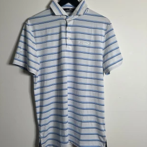 Piké RLX Ralph Lauren  - Piké i vit med blåa ränder från Ralph Lauren. Använd fåtal gånger och är i mycket fint skick. Storlek M. Nypris: runt 1500kr
