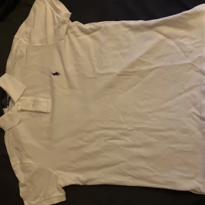 Vit pikétröja från Polo Ralph Lauren - Säljer en klassisk vit pikétröja från Polo Ralph Lauren i storlek M. Tröjan har korta ärmar och en broderad logga på bröstet. Perfekt för en stilren och avslappnad look.            Skick 9/10              !!!Fraktar samma dag som ni köper ‼️