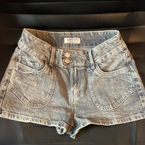Gråa tajta korta shorts från Lindex storlek 11-12y 💕💕 - Shortsen är korta och tajta i en ljusgrå färg. Shortsen har 2 knappar och 5 fickor 💕💕