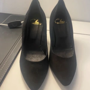 Svarta pumps från Clou - Säljer ett par eleganta svarta pumps från Clou i storlek 37. Skorna har en spetsig tå och en stabil klack, perfekta för både fest och vardag. De är i bra skick och redo att användas för att ge din outfit en stilfull touch.