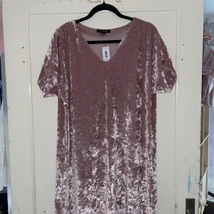 Rosa sammet klänning från MyWear Woman - Säljer en superfin rosa klänning i sammet från MyWear Woman. Den har en v-ringad hals och korta ärmar, perfekt för en festlig kväll. Klänningen är i storlek M och har en härlig glansig finish som verkligen sticker ut.