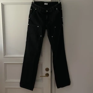 Svarta byxor från Filippa K - Säljer ett par snygga svarta byxor från Filippa K. De har en stilren design med knappar som detaljer och en rak passform. Ganska lågmidjade.