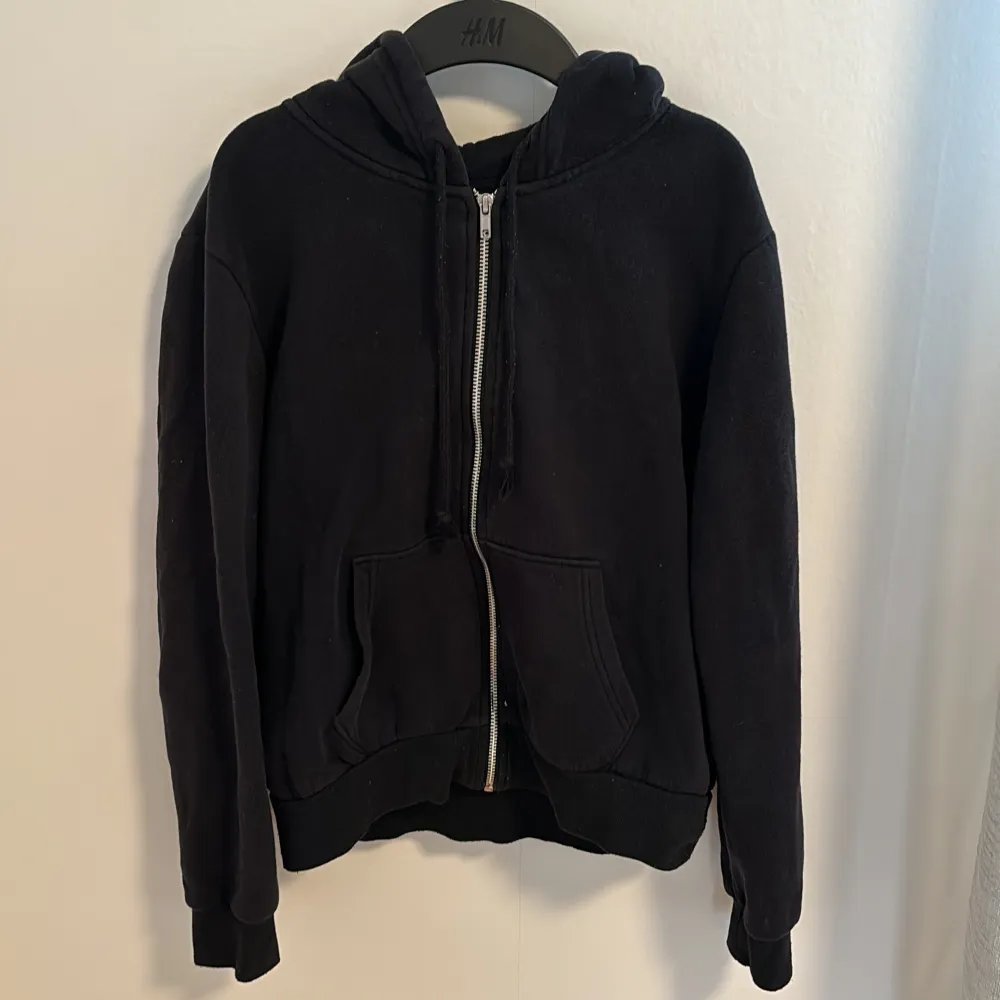 Säljer en svart hoodie från H&M Divided i storlek M. Den har en dragkedja framtill och två fickor.  Hoodien är i bra skick men lite nopprig på snörena! Inget som inte går att få bort :). Tröjor & Koftor.